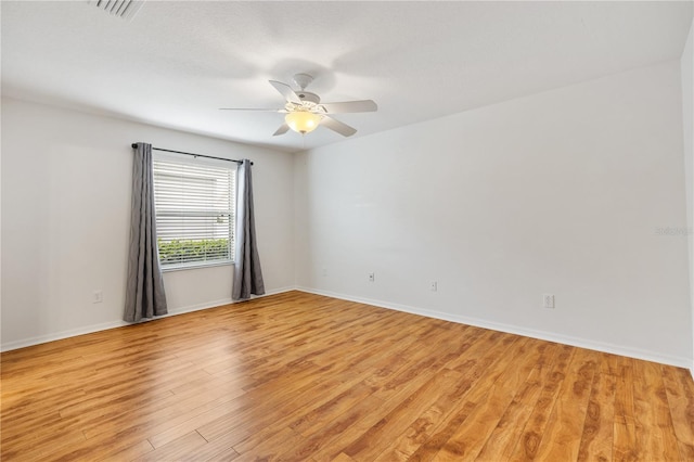 spare room with light wood-style flooring, visible vents, ceiling fan, and baseboards