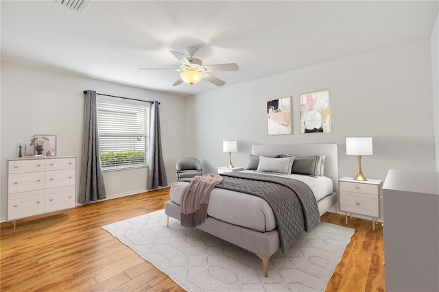 bedroom with a ceiling fan, visible vents, and light wood finished floors