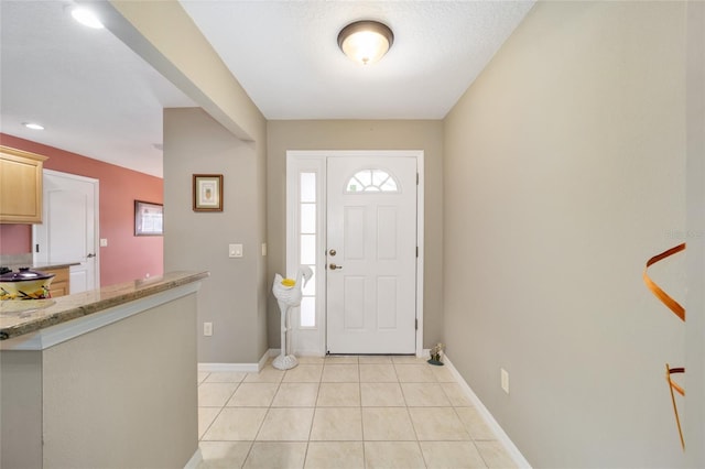 foyer with a wealth of natural light, baseboards, and light tile patterned floors