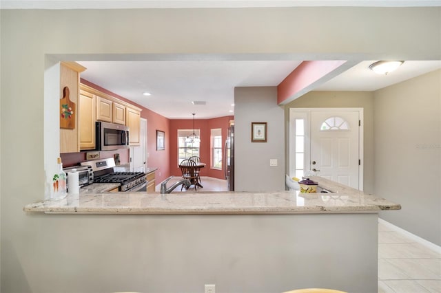 kitchen featuring light stone counters, light brown cabinets, a peninsula, hanging light fixtures, and appliances with stainless steel finishes