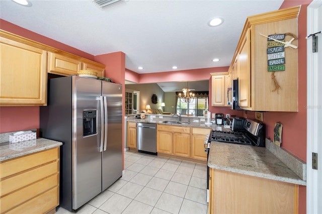 kitchen with light tile patterned floors, light brown cabinets, a sink, appliances with stainless steel finishes, and an inviting chandelier