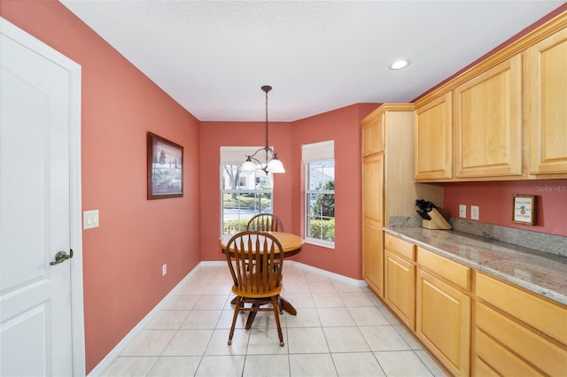 kitchen with light stone counters, light brown cabinetry, baseboards, and light tile patterned floors