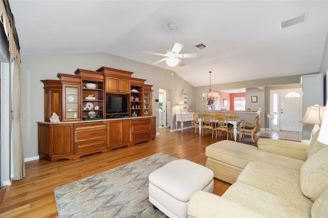 living area featuring light wood-type flooring, visible vents, vaulted ceiling, and ceiling fan with notable chandelier