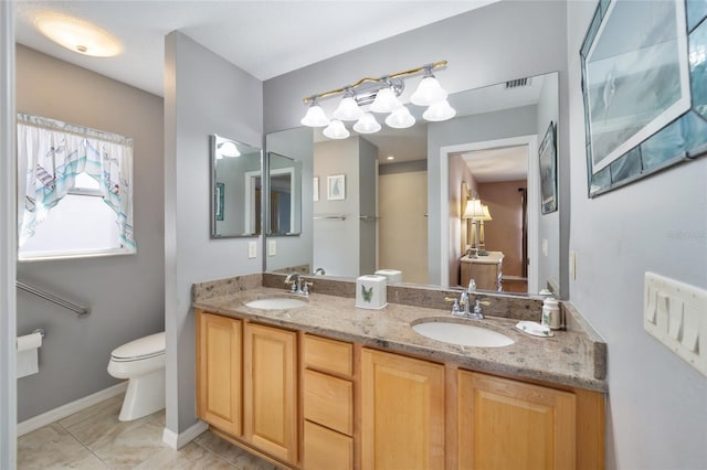 bathroom featuring visible vents, double vanity, a sink, and toilet