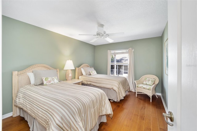 bedroom featuring a ceiling fan, a textured ceiling, baseboards, and wood finished floors