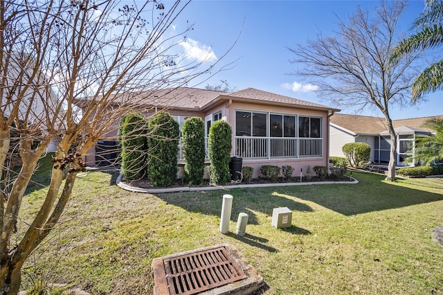 view of side of home with a sunroom, a lawn, and stucco siding