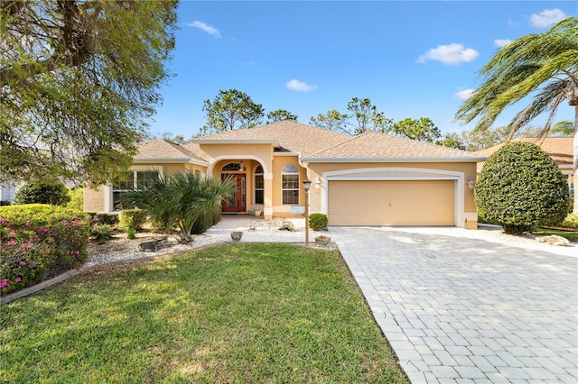 ranch-style home featuring a front lawn, decorative driveway, an attached garage, and stucco siding