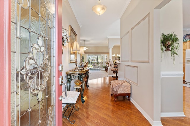 foyer entrance with ornamental molding, an inviting chandelier, wood finished floors, and baseboards