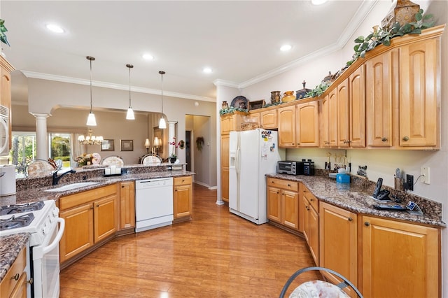 kitchen featuring white appliances, decorative light fixtures, ornate columns, light wood-style floors, and a sink