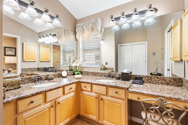 bathroom with tile patterned flooring, vaulted ceiling, a sink, and double vanity