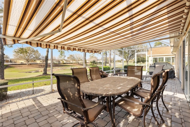 view of patio featuring glass enclosure, outdoor dining space, and grilling area