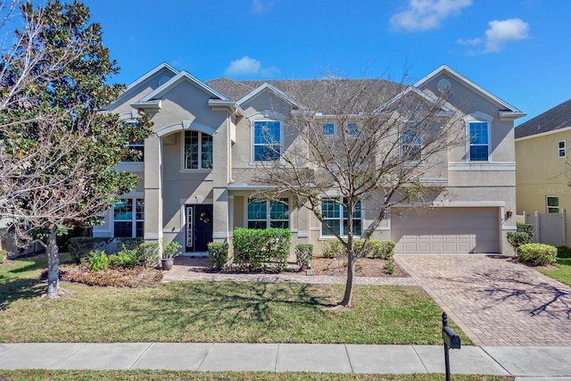 view of front of property featuring a garage, a front lawn, decorative driveway, and stucco siding