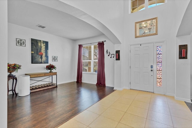 entryway featuring light wood-type flooring, arched walkways, visible vents, and baseboards