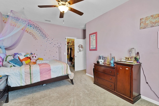 bedroom with a walk in closet, visible vents, light carpet, ceiling fan, and baseboards