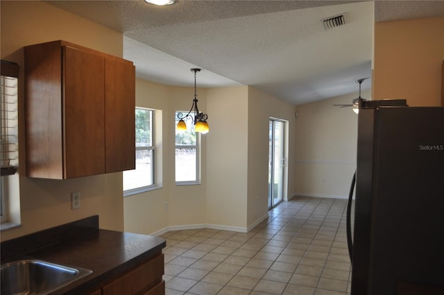 kitchen with light tile patterned floors, visible vents, dark countertops, decorative light fixtures, and freestanding refrigerator