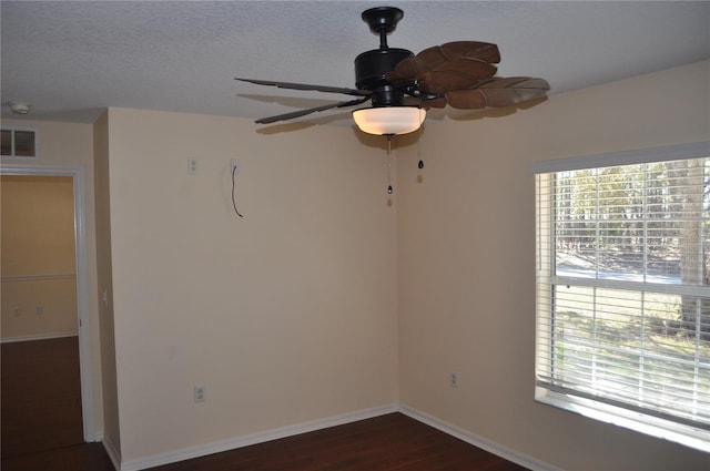 empty room featuring a textured ceiling, a wealth of natural light, visible vents, and baseboards