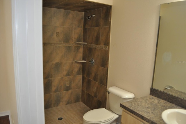 full bathroom featuring a tile shower, vanity, and toilet