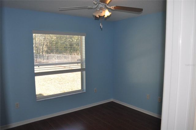 unfurnished room featuring dark wood finished floors, a ceiling fan, and baseboards