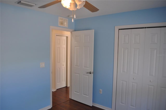 unfurnished bedroom with a closet, dark wood-style flooring, visible vents, and baseboards