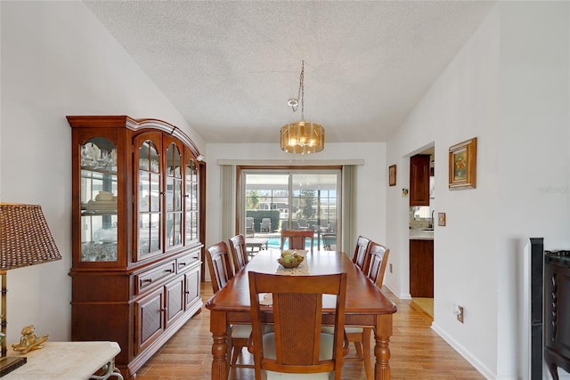 12338 S Putney Ct, Leesburg, FL 34788 - dining room featuring lofted ceiling, a textured ceiling, light wood finished floors, and an inviting chandelier