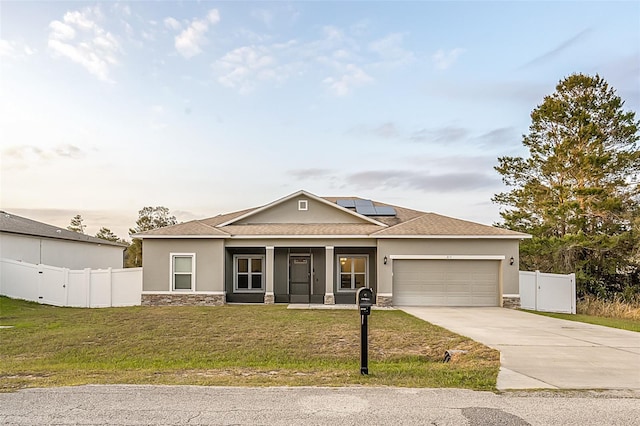 view of front facade featuring stucco siding, a front yard, roof mounted solar panels, a garage, and stone siding