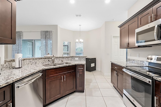 kitchen featuring stainless steel appliances, a sink, visible vents, hanging light fixtures, and dark brown cabinets