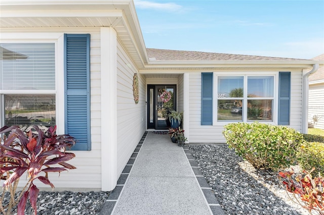 view of exterior entry with a shingled roof