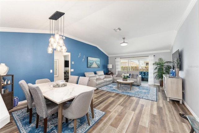 dining area featuring vaulted ceiling, wood finished floors, visible vents, and crown molding