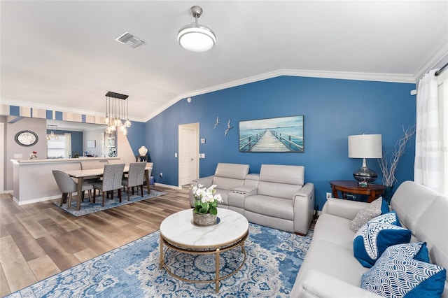 living room with crown molding, visible vents, vaulted ceiling, and wood finished floors