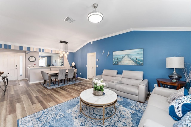 living area featuring crown molding, visible vents, vaulted ceiling, wood finished floors, and baseboards