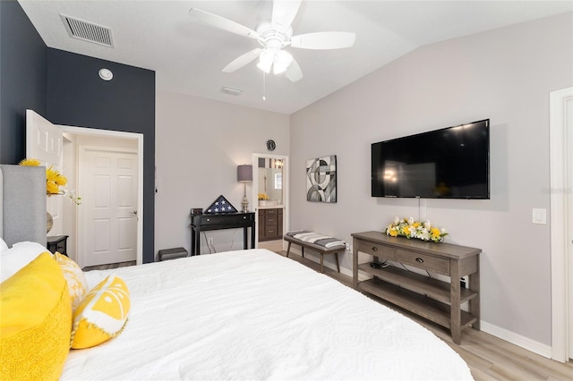 bedroom with lofted ceiling, visible vents, light wood-style floors, connected bathroom, and baseboards