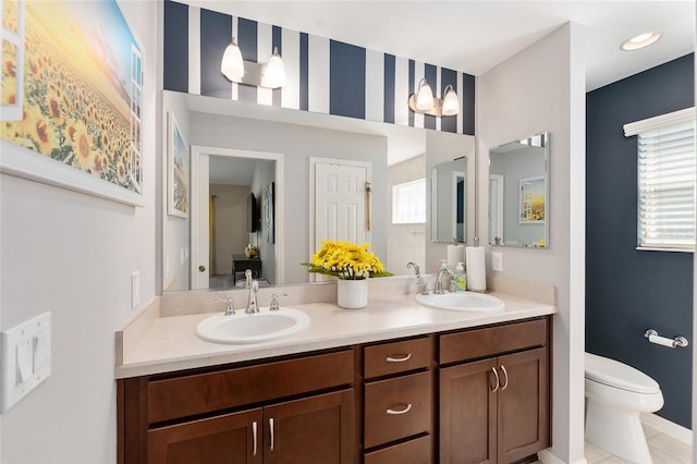 full bathroom with toilet, double vanity, and a sink