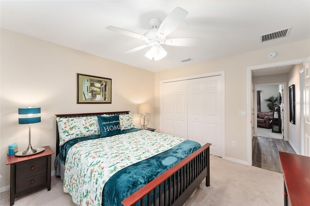 bedroom with light colored carpet, a ceiling fan, baseboards, visible vents, and a closet