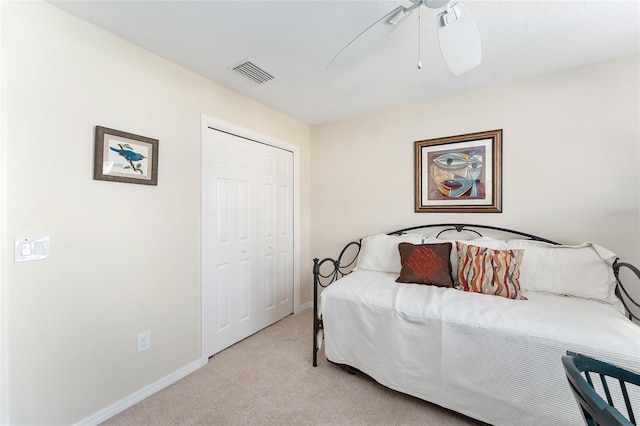 bedroom featuring baseboards, visible vents, light colored carpet, ceiling fan, and a closet