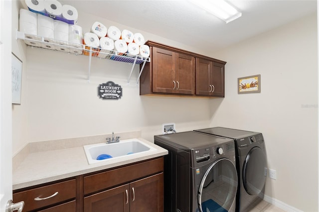 washroom featuring cabinet space, baseboards, independent washer and dryer, tile patterned flooring, and a sink