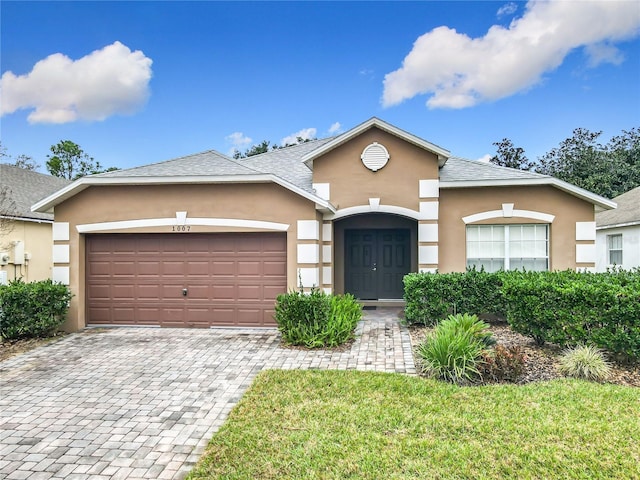 view of front of property with decorative driveway, an attached garage, and stucco siding