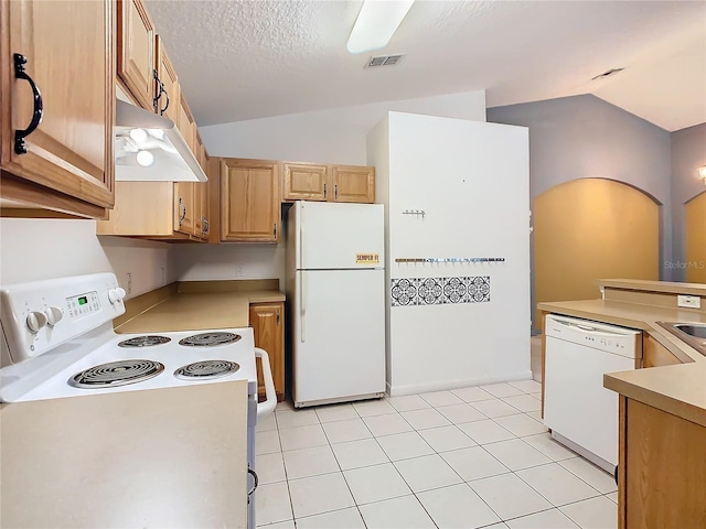 kitchen with under cabinet range hood, white appliances, visible vents, vaulted ceiling, and light countertops