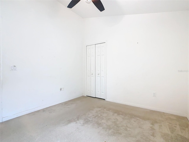 unfurnished bedroom with lofted ceiling, light carpet, a ceiling fan, baseboards, and a closet