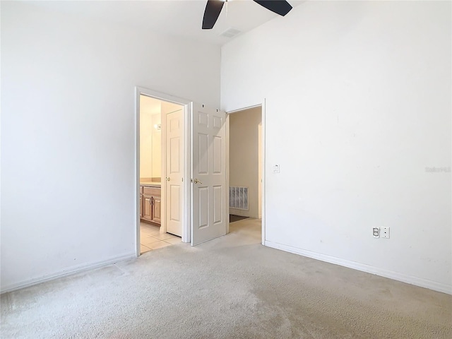 unfurnished bedroom featuring light carpet, ensuite bath, visible vents, and baseboards