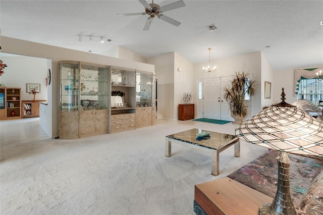 25274 Lost Oak Cir, Leesburg, FL 34748 - living room with light carpet, visible vents, lofted ceiling, a textured ceiling, and ceiling fan with notable chandelier