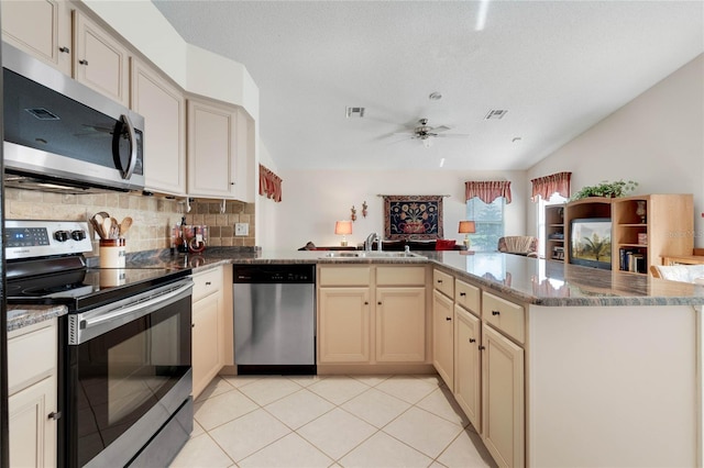 25274 Lost Oak Cir, Leesburg, FL 34748 - kitchen with lofted ceiling, appliances with stainless steel finishes, open floor plan, a peninsula, and cream cabinets
