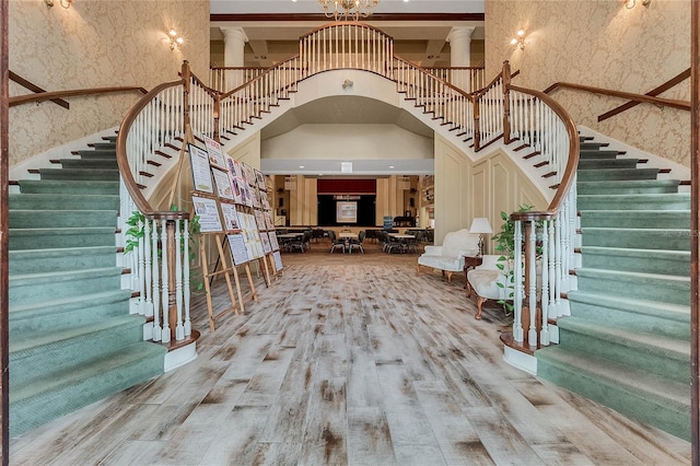 25274 Lost Oak Cir, Leesburg, FL 34748 - foyer featuring wallpapered walls, a towering ceiling, wood finished floors, stairs, and ornate columns