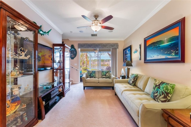 living area featuring a ceiling fan, visible vents, crown molding, and light colored carpet