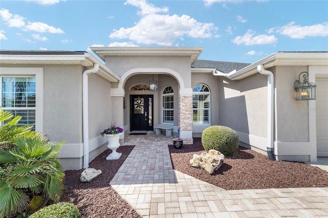 entrance to property with a garage and stucco siding