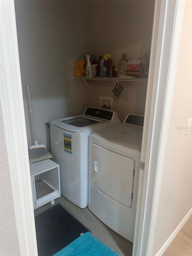 washroom with baseboards and washing machine and clothes dryer
