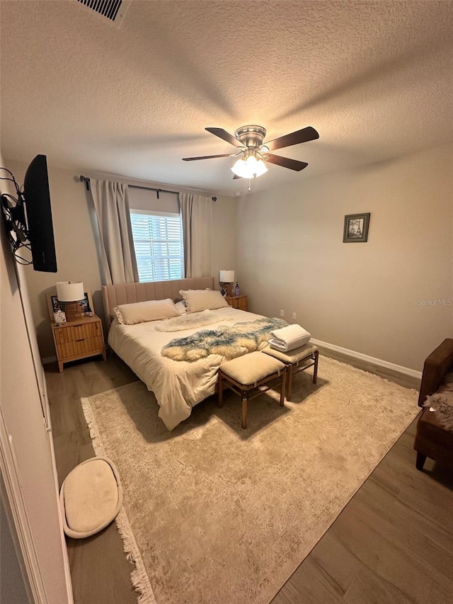 bedroom with a ceiling fan, dark wood-style flooring, a textured ceiling, and baseboards