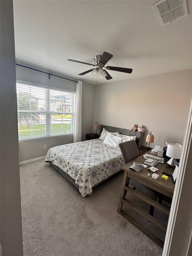 carpeted bedroom with a textured ceiling, ceiling fan, visible vents, and baseboards