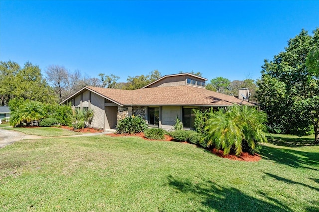 view of front of home featuring roof with shingles and a front yard