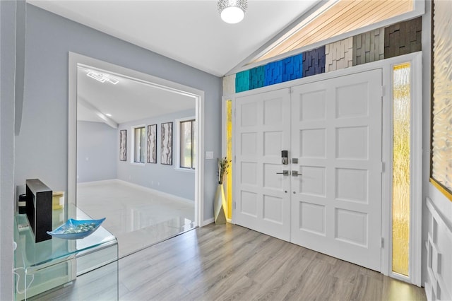 foyer with vaulted ceiling, wood finished floors, and baseboards