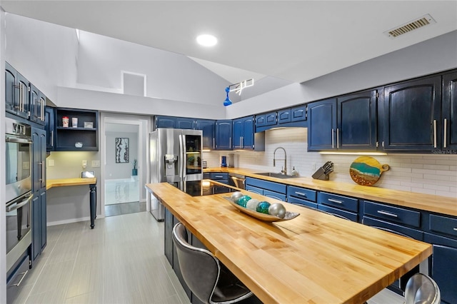 kitchen featuring visible vents, blue cabinetry, wooden counters, and a sink